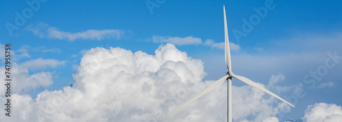Photography Panoramic view of the blades of a wind turbine over a blue sky with large clouds