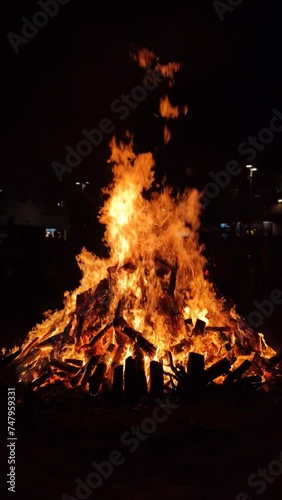 View of a large bonfire lit at night as part of popular and ancestral celebrations in the squares of villages and cities from the Mediterranean. Vertical format