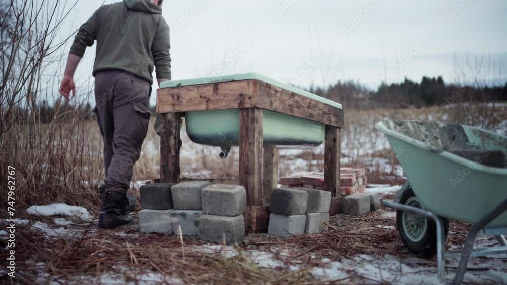 The Man is Removing Bricks From the Wheelbarrow and Placing them Near the DIY Hot Tub - Static Shot The Man is Removing Bricks From the Wheelbarrow and Placing them Near the DIY Hot Tub - Static Shot