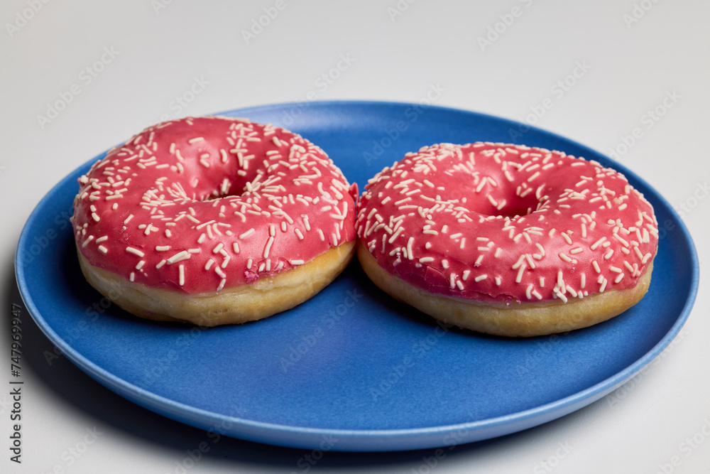 donuts with pink frosting on a plate. donuts with pink frosting on a plate.