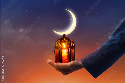 Hand holding  Arabic Ramadan Lantern. Decoration lamp. Crescent moon and the stars. Islamic greeting Eid Mubarak cards for Muslim Holidays.Eid-Ul-Adha festival celebration