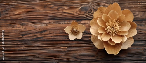 A paper flower placed on a wooden background creates an intriguing blend of textures and colors. The delicate petals of the flower stand out against the rugged surface of the wood.