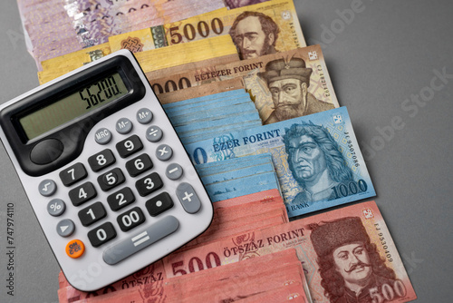 On a gray table, Hungarian forint paper money is spread out and sorted. Large denominations, calculator, Inflation and financial situation in Hungary.