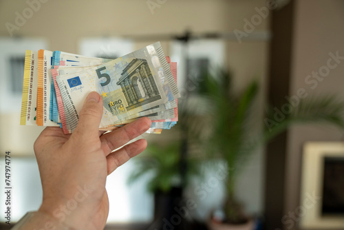 A man holds money in his hand. Cash in euros for payment or exchange. The man counts the payment in euro banknotes. Saving money, taking a bank deposit. European money. Financial crisis.