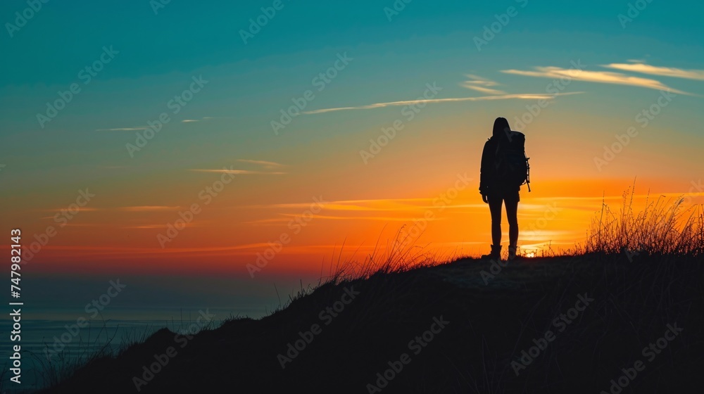 a person standing on a hill with a sunset in the background