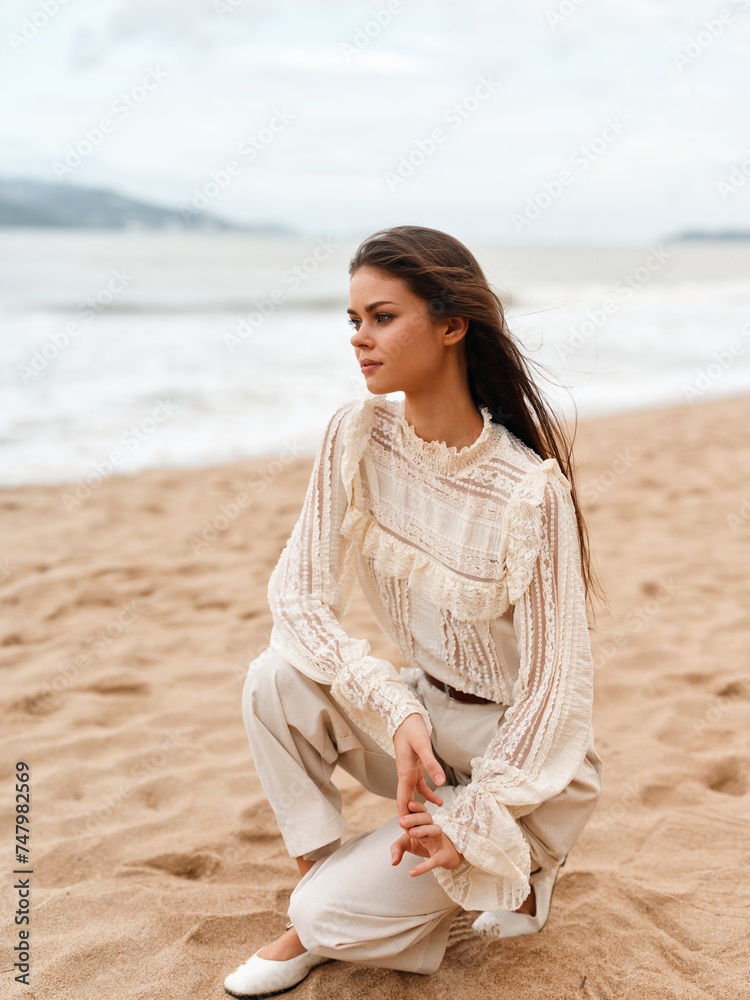 Sitting on the Beach, a Beautiful Caucasian Woman in a Stylish White Dress Embracing the Summer Vibes Sitting on the Beach, a Beautiful Caucasian Woman in a Stylish White Dress Embracing the Summer Vibes