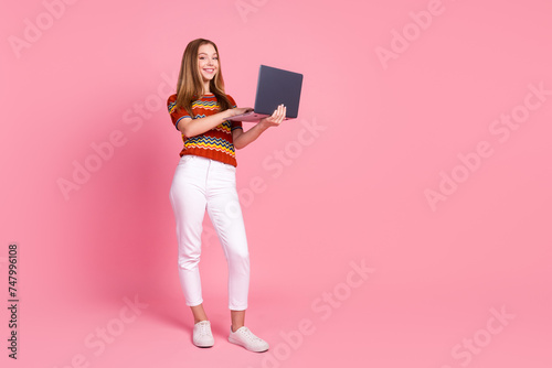 Full size portrait of lovely positive girl hold use netbook chatting social network empty space isolated on pink color background