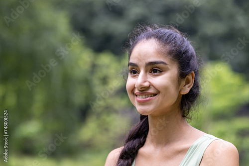 Radiant young indian woman smiling in sportswear enjoying nature in a lush park