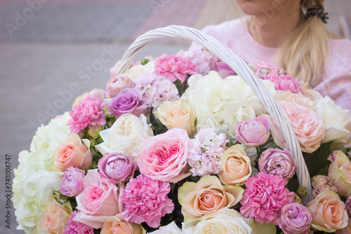 Girl florist holding a basket of flowers in her hands photo