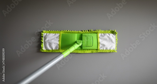 Top view of green mop with handle for floor cleaning. Macro shot of fluffy rag. Equipment of professional cleaner. Renovation and springcleaning concept photo
