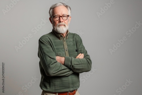 Portrait of senior man with gray beard, retiree in green sweater and glasses