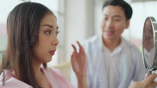 Asian woman patient take off the face mask and looking at a mirror while listening surgeon explaining cosmetic surgery in surgery clinic. Plastic surgery, Cosmetic surgery concept photo