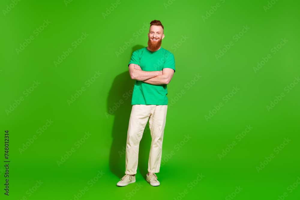 Full length photo of funky confident guy wear t-shirt smiling arms crossed empty space isolated green color background Full length photo of funky confident guy wear t-shirt smiling arms crossed empty space isolated green color background