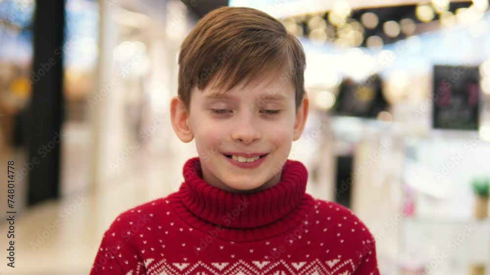 The joy of Christmas. Smiling Caucasian boy 9 years old in a New Year's sweater in a shopping center during the week of Christmas sales, smiling looking at the camera The joy of Christmas. Smiling Caucasian boy 9 years old in a New Year's sweater in a shopping center during the week of Christmas sales, smiling looking at the camera