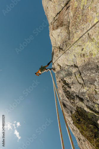 woman climbing in the mountain at sunset with lus rays, security, confidence business woman, rope access, life insurance. photo