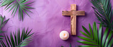 Wooden cross with a burning candle on a purple background with palm leaves.