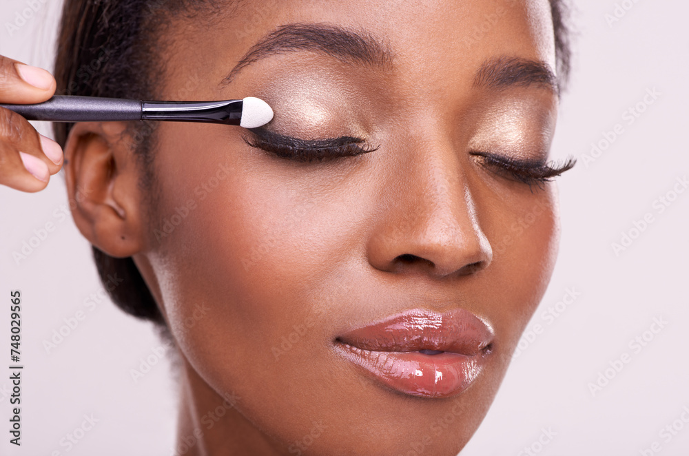Black woman, face and brush for eyeshadow with makeup, beauty and lashes isolated on pink background. Skin glow, cosmetics product and tools for cosmetology, shimmer or glitter with shine in studio