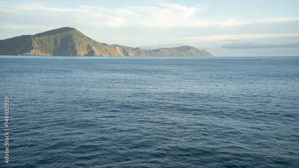 View on hilly landscape from passing transport boat during its sail, New Zealand