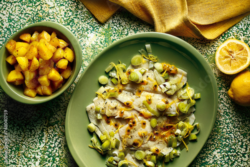 prato com peixe ao molho de alho-poró e maracujá acompanhado de batatas assadas sobre mesa