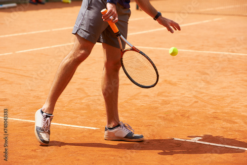 Tennis, court and legs of person outdoor at start of exercise of workout in competition. Athlete, serving and sneakers of player training with ball on clay pitch in sport, game and action in fitness