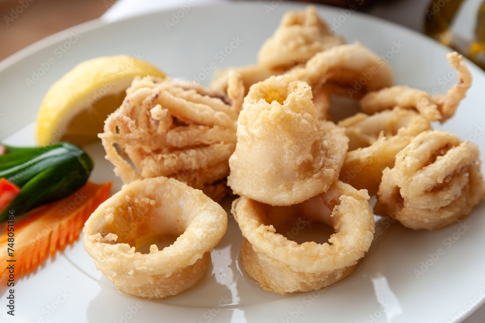 Close up of fried squid in batter served on a white plate in a mediterranean restaurant.