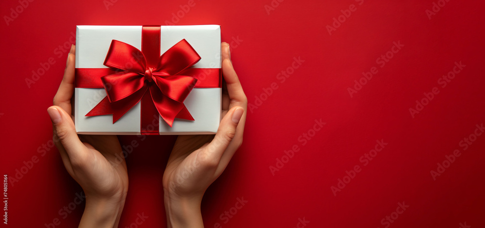 Top view of hand holding red gift box on isolated red background, copy space area Top view of hand holding red gift box on isolated red background, copy space area