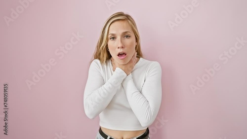 Young blonde woman in pain, suffocating and asphyxiating due to strangle attempt over isolated pink background, severe health problem photo