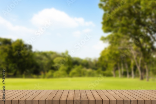 Wooden table top on park with green grass field in city and a cloudy bluesky background. Empty Wooden tabletop used for advertising products or products