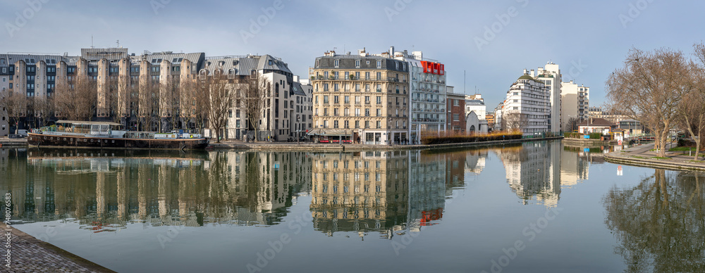 Paris, France - 01 27 2024: Ourcq Canal. Reflections on the Ourcq canal of residential buildings, bridge, barges and The Stalingrad Rotunda .
