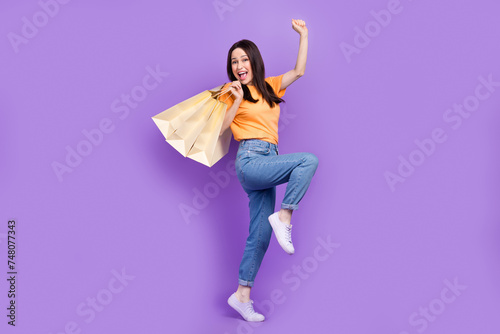 Full length size photo of overjoyed business woman in yellow t shirt and jeans buy more clothes hobby isolated on violet color background