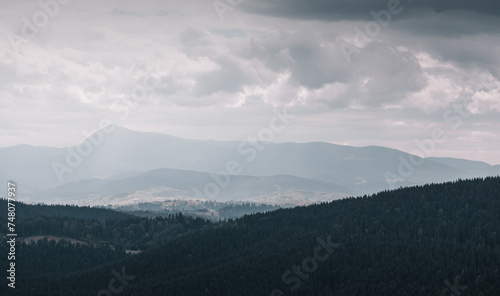 Rainy weather in mountains - gray cloudy day in Carpathian mountains. View from the top of Bukovel mountain at the second highest mountain in Ukraine - Petros (Chornohora) mountain peak (2020m). 