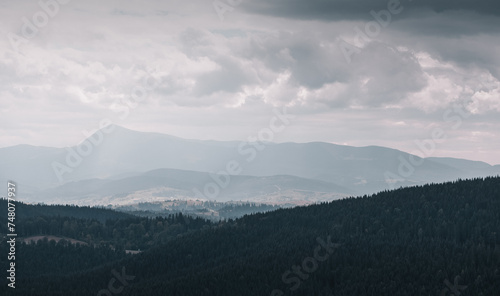 Fototapeta Naklejka Na Ścianę i Meble -  Rainy weather in mountains - gray cloudy day in Carpathian mountains. View from the top of Bukovel mountain at the second highest mountain in Ukraine - Petros (Chornohora) mountain peak (2020m). 