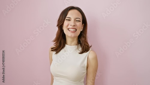 Young beautiful hispanic woman in sleeveless tee, standing with her tongue out, donning a funny face. capturing pure joy, her happiness shines over an isolated pink background. photo