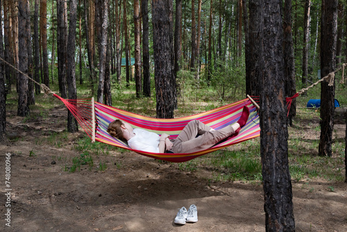 Beautiful young woman relaxing in hammock in forest. Summer scenery, a beautiful morning in the bosom of nature. The girl admires the views and nature. Breathed fresh air. Beautiful morning light.