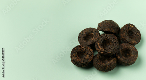A pile of high quality fifteen years old pressed Pu Erh Mini Tou Cha tea. Empty blue green background with space for text. photo