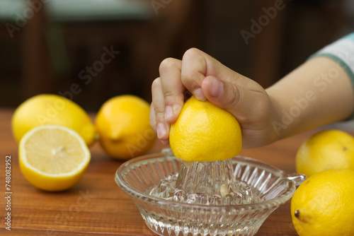 Little Child hand squeeze lemon juice with a lemon glass squeezer. Family cooking concept. 