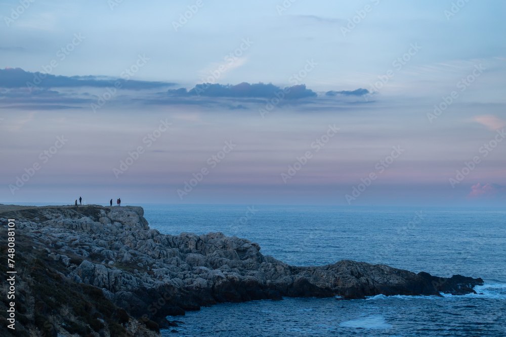 People on a cliff at the sunset