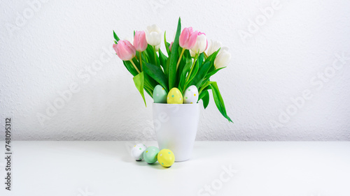 Easter eggs near a bouquet of spring natural fresh tulips flowers. Easter greeting card. White background.