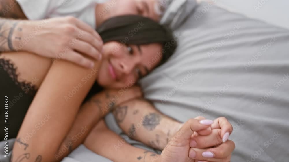 Intimate couple with tattoos embracing in a cozy bedroom, conveying love and connection in a home setting. Intimate couple with tattoos embracing in a cozy bedroom, conveying love and connection in a home setting.