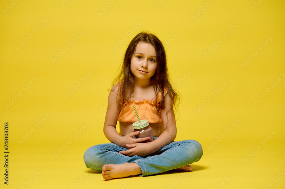 Funny little child girl with a glass of cocktail on a yellow background Funny little child girl with a glass of cocktail on a yellow background