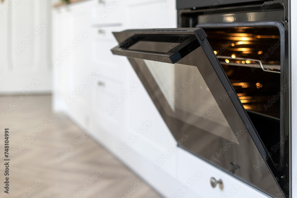 Selective focus on opened glass door with handle of modern electric oven Selective focus on opened glass door with handle of modern electric oven