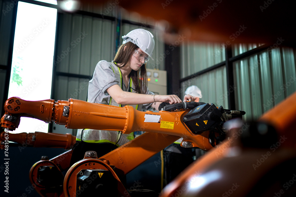 Fototapeta premium Factory engineers inspecting on machine with smart tablet. Worker works at heavy machine robot arm. The welding machine with a remote system in an industrial factory. Artificial intelligence concept.