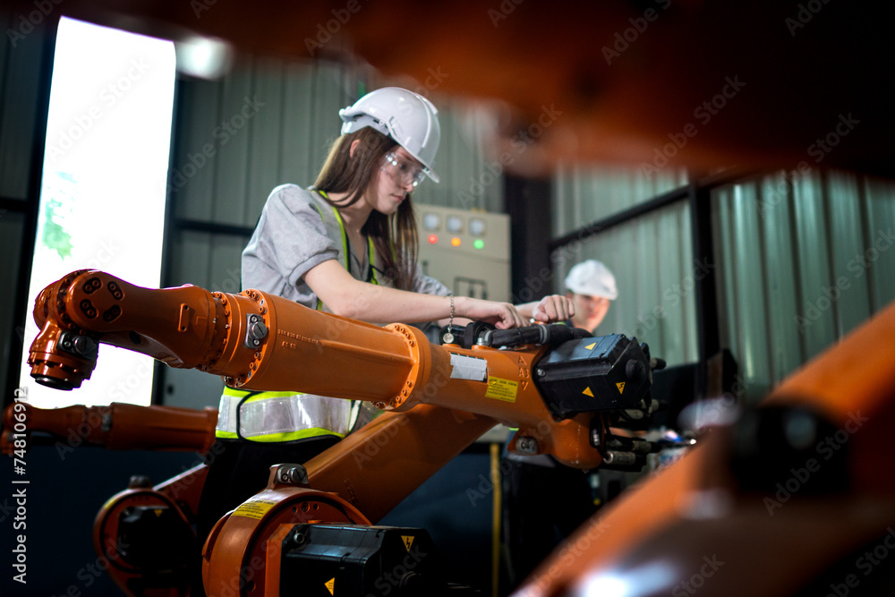 Factory engineers inspecting on machine with smart tablet. Worker works at heavy machine robot arm. The welding machine with a remote system in an industrial factory. Artificial intelligence concept. Factory engineers inspecting on machine with smart tablet. Worker works at heavy machine robot arm. The welding machine with a remote system in an industrial factory. Artificial intelligence concept.