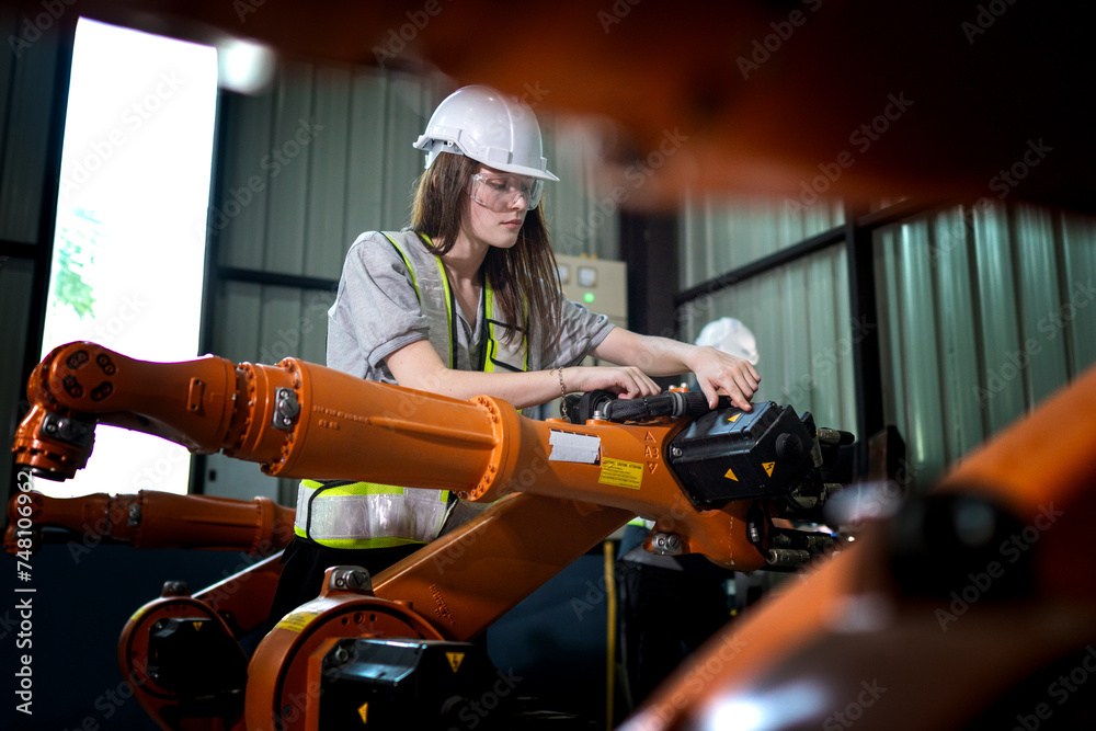 Factory engineers inspecting on machine with smart tablet. Worker works at heavy machine robot arm. The welding machine with a remote system in an industrial factory. Artificial intelligence concept. Factory engineers inspecting on machine with smart tablet. Worker works at heavy machine robot arm. The welding machine with a remote system in an industrial factory. Artificial intelligence concept.