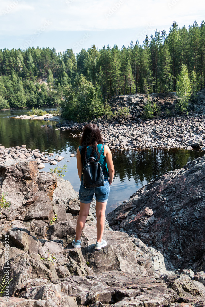 Girvas paleovolcano is a popular place among tourists. The concept of traveling around Russia. A tourist stands on frozen lava and enjoys the view of the lake. Back view.