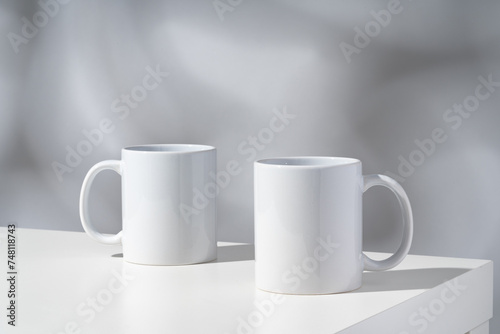 White ceramic mugs on gray background with shadows