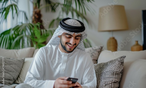 Arab man with phone smiling texting browsing app in living room