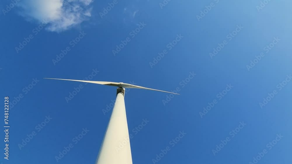Wind generator against a blue sky with clouds. Rotation of white wind turbine blades Wind generator against a blue sky with clouds. Rotation of white wind turbine blades