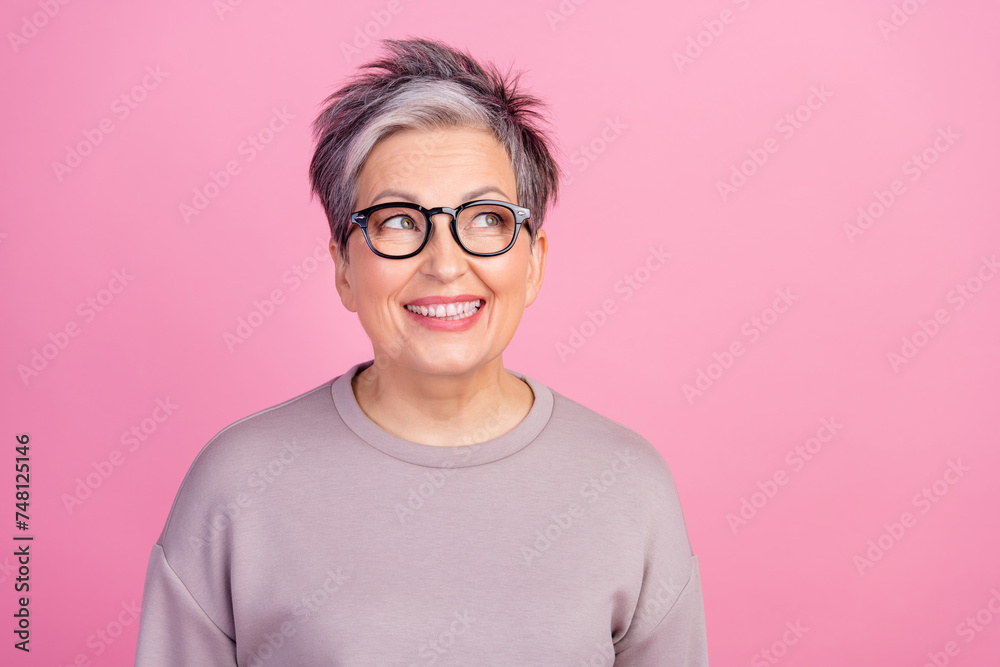 Photo of grandmother grey short haircut woman in violet sweatshirt smiling looking empty space thoughtful isolated on pink color background