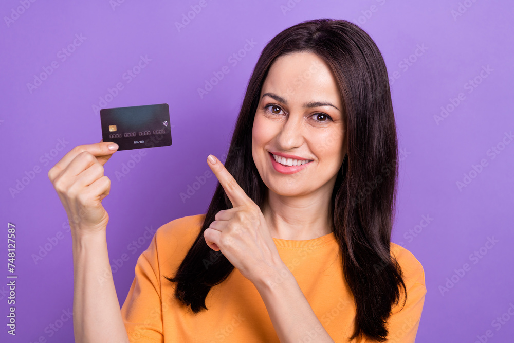 Portrait of pleasant nice girl with stylish hairdo wear oversize t-shirt indicating at debit card isolated on violet color background Portrait of pleasant nice girl with stylish hairdo wear oversize t-shirt indicating at debit card isolated on violet color background